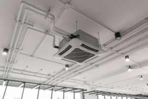 Modern white ceiling mounted cassette type air conditioner in office building system work. Ventilation compressor.