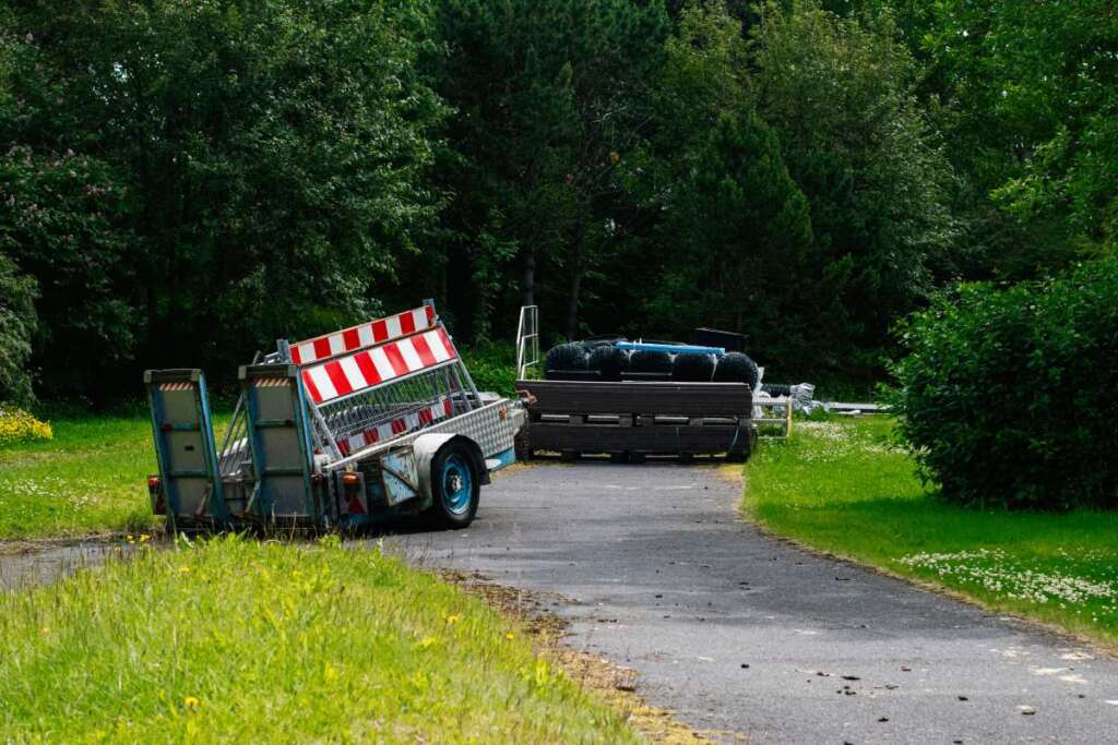 Utility trailers parked on a countryside road amidst lush green surroundings
